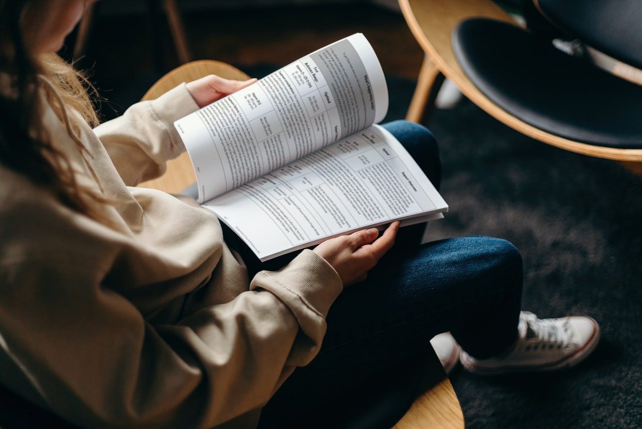 Woman in Long Sleeve Shirt Holding Book